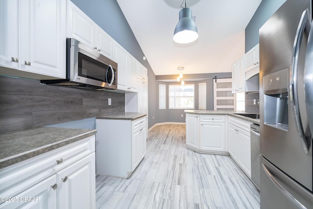 kitchen featuring appliances with stainless steel finishes, white cabinetry, decorative light fixtures, and tasteful backsplash