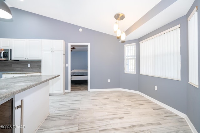 kitchen with vaulted ceiling, white cabinets, decorative backsplash, and pendant lighting