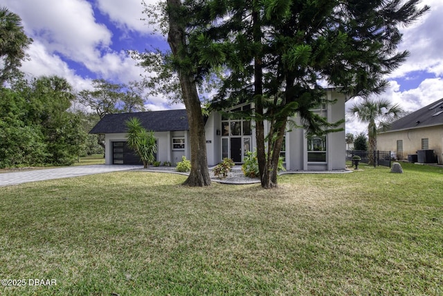 view of front facade with cooling unit, a garage, and a front lawn