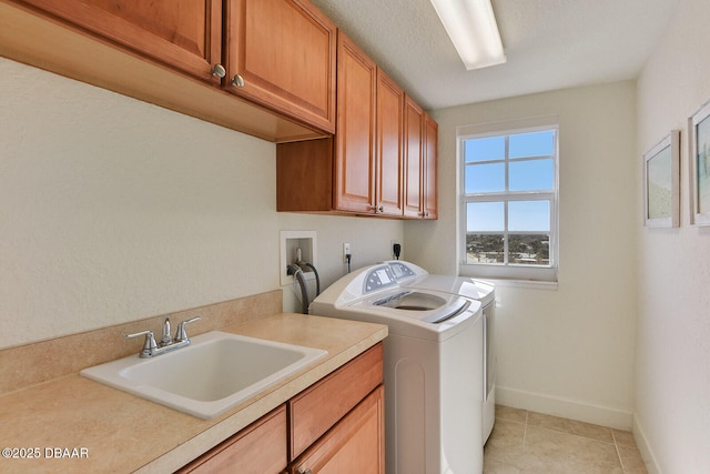 laundry room with independent washer and dryer, a sink, cabinet space, light tile patterned floors, and baseboards