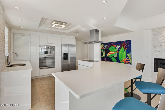 kitchen with island exhaust hood, a sink, appliances with stainless steel finishes, white cabinetry, and modern cabinets