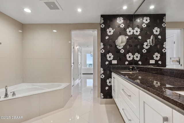 bathroom with visible vents, double vanity, a sink, a garden tub, and tile patterned floors