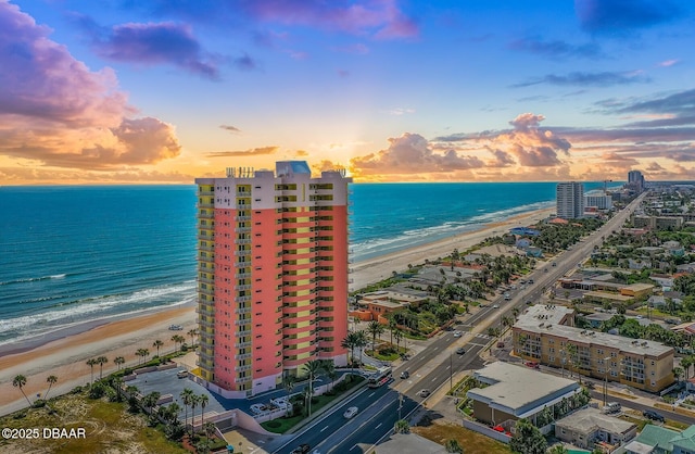 aerial view at dusk with a water view, a city view, and a view of the beach