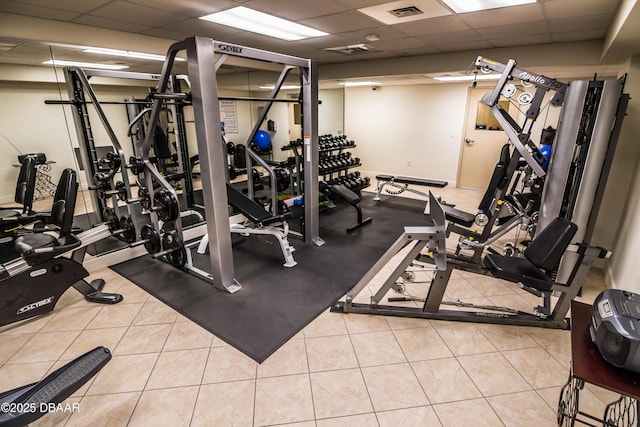 exercise room with a drop ceiling, visible vents, and tile patterned flooring