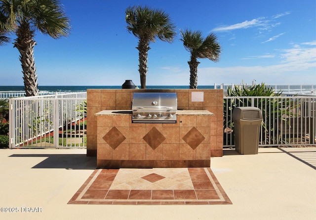 view of patio with grilling area, a water view, and exterior kitchen