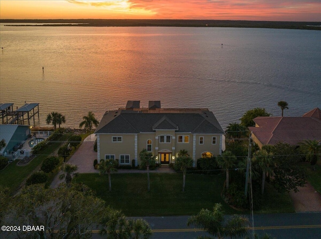 aerial view at dusk featuring a water view