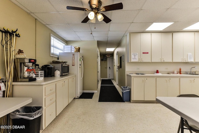 59 Cardinal Dr Unit A, Ormond Beach, FL 32176 - kitchen featuring a drop ceiling, light countertops, stainless steel microwave, ceiling fan, and dark speckled floor