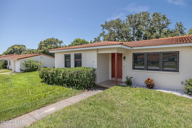 59 Cardinal Dr Unit A, Ormond Beach, FL 32176 - view of front of house with brick siding, a front yard, and a tiled roof