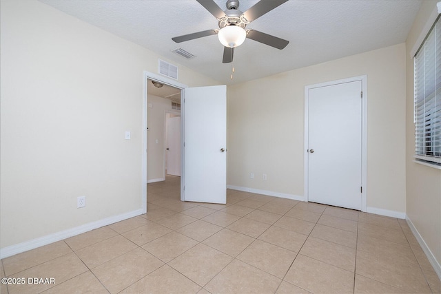 59 Cardinal Dr Unit A, Ormond Beach, FL 32176 - unfurnished bedroom featuring light tile patterned floors, a textured ceiling, and a ceiling fan