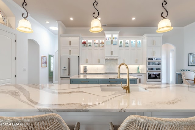 kitchen featuring decorative backsplash, white cabinets, white appliances, arched walkways, and a sink