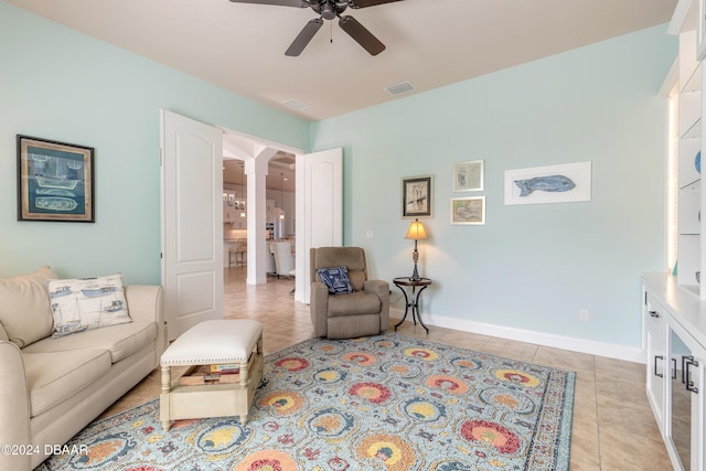 living area with ornate columns, light tile patterned flooring, arched walkways, visible vents, and ceiling fan