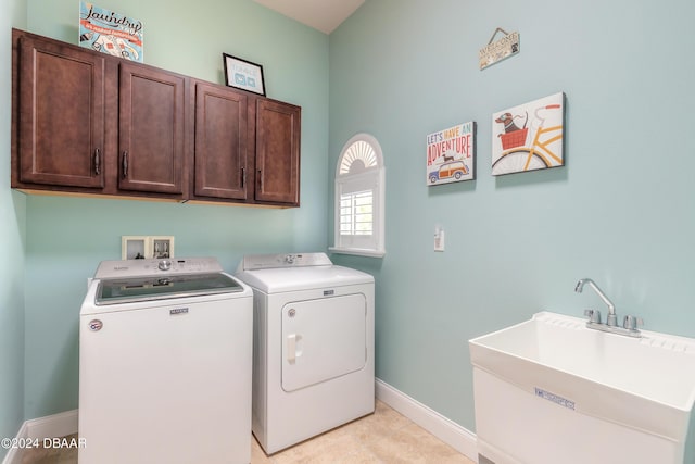 washroom with washing machine and dryer, a sink, light tile patterned floors, baseboards, and cabinet space