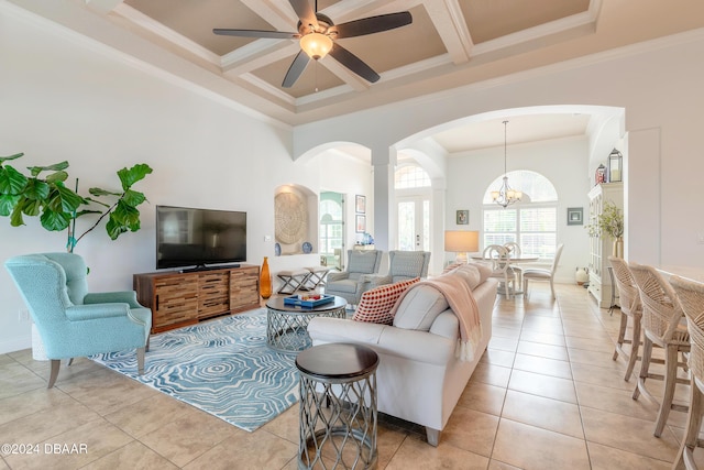living room with coffered ceiling, light tile patterned flooring, ceiling fan with notable chandelier, arched walkways, and a towering ceiling