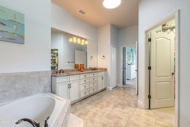 full bath featuring visible vents, double vanity, tile patterned floors, a sink, and a garden tub