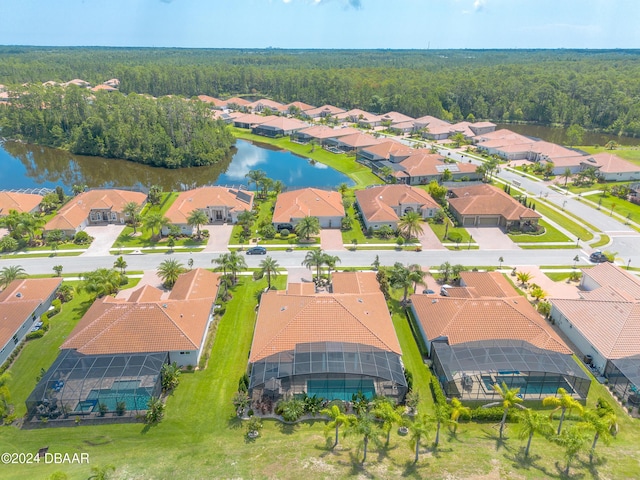 drone / aerial view featuring a residential view, a water view, and a view of trees