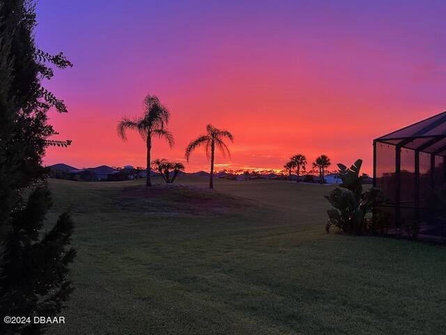 yard at dusk featuring a lanai