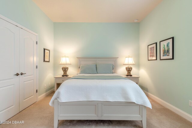 bedroom with light carpet, baseboards, and a closet