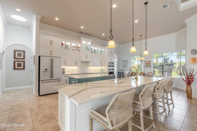 kitchen with crown molding, a large island, white appliances, visible vents, and decorative backsplash