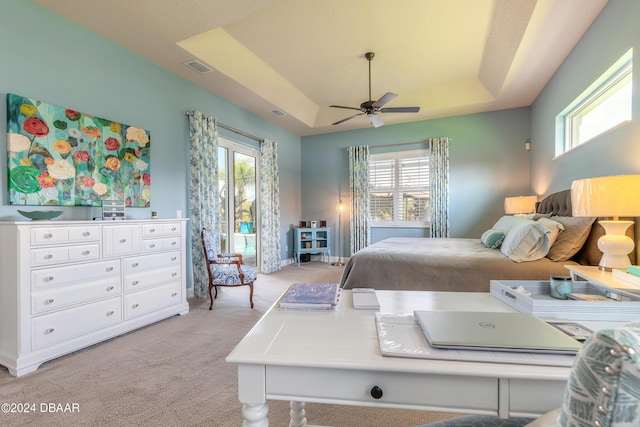 bedroom featuring visible vents, light carpet, multiple windows, and a raised ceiling