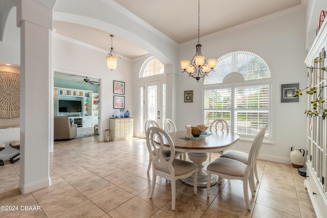 dining area featuring a healthy amount of sunlight, ornamental molding, baseboards, a towering ceiling, and arched walkways