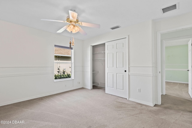 unfurnished bedroom featuring a closet, light colored carpet, and ceiling fan