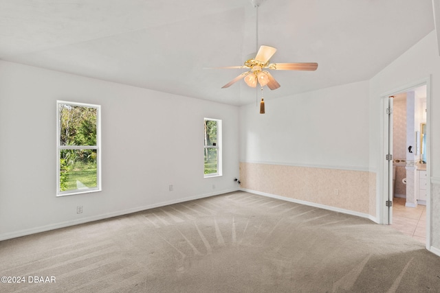 carpeted spare room featuring lofted ceiling and ceiling fan