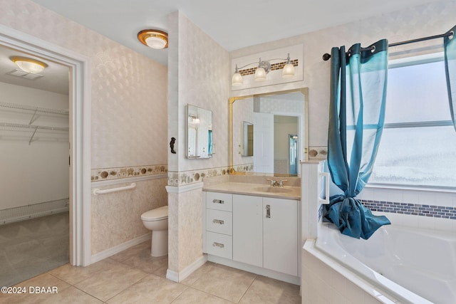 bathroom featuring vanity, tile patterned floors, toilet, and tiled tub