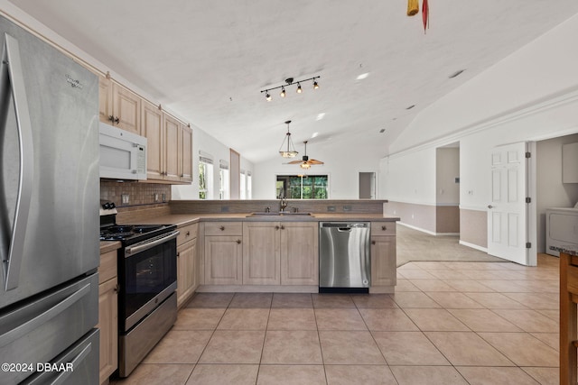 kitchen with vaulted ceiling, sink, light tile patterned floors, appliances with stainless steel finishes, and light brown cabinetry