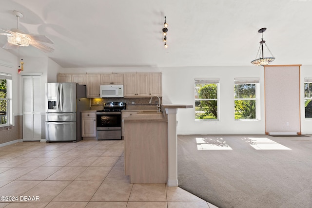 kitchen with stainless steel appliances, light colored carpet, vaulted ceiling, sink, and pendant lighting