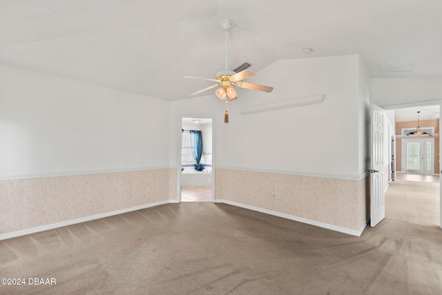 empty room featuring ceiling fan, a wealth of natural light, light colored carpet, and vaulted ceiling