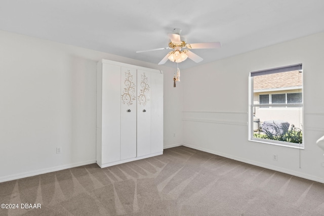 unfurnished bedroom featuring light colored carpet, ceiling fan, and a closet