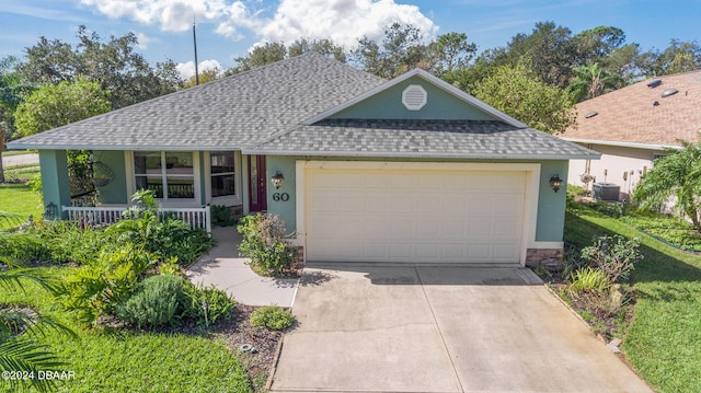 single story home with central AC unit, a garage, a front yard, and a porch