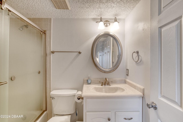 full bathroom featuring bath / shower combo with glass door, vanity, a textured ceiling, and toilet