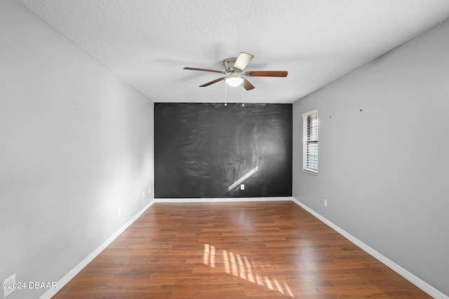 empty room with a textured ceiling, dark hardwood / wood-style flooring, and ceiling fan