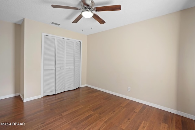 unfurnished bedroom featuring a textured ceiling, ceiling fan, dark wood-type flooring, and a closet