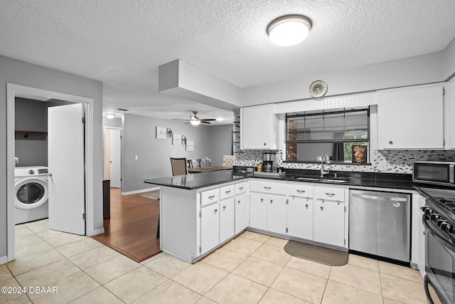 kitchen with kitchen peninsula, stainless steel appliances, sink, white cabinets, and washer / clothes dryer