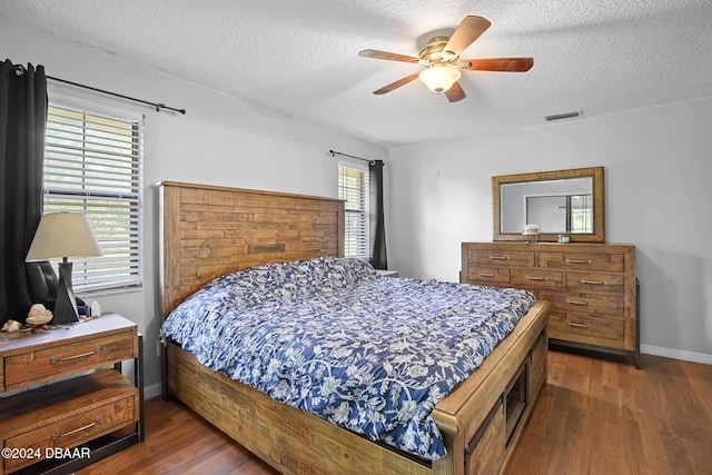 bedroom featuring dark hardwood / wood-style floors, ceiling fan, and a textured ceiling