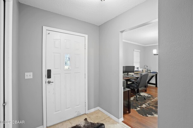 entryway featuring light hardwood / wood-style floors, a textured ceiling, and ornamental molding