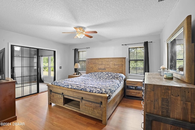 bedroom with a textured ceiling, light hardwood / wood-style floors, and ceiling fan