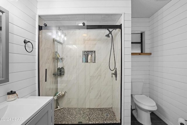 bathroom featuring wooden walls, vanity, an enclosed shower, and toilet