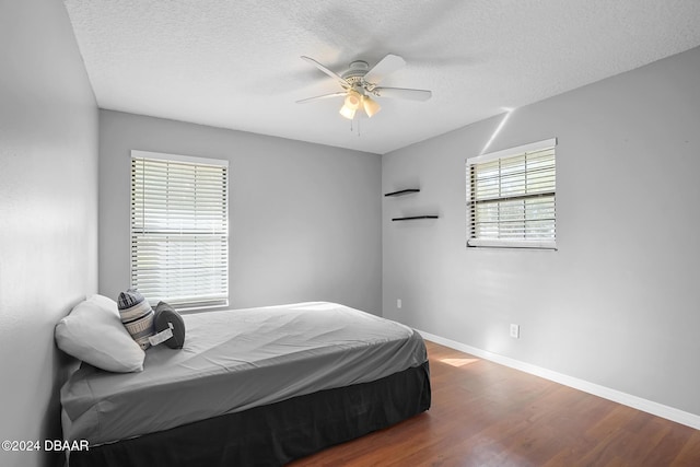 bedroom featuring hardwood / wood-style flooring, ceiling fan, a textured ceiling, and multiple windows