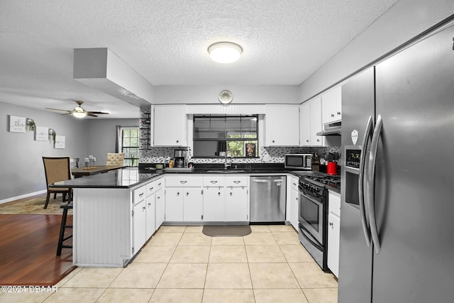 kitchen featuring kitchen peninsula, appliances with stainless steel finishes, a kitchen bar, and white cabinets