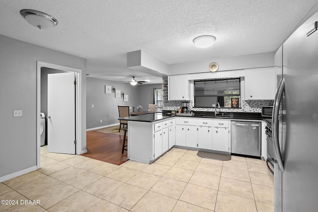 kitchen featuring kitchen peninsula, stainless steel appliances, ceiling fan, sink, and white cabinets