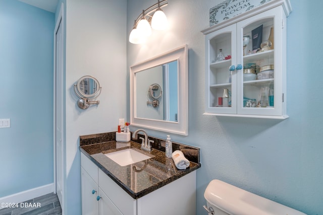 bathroom with hardwood / wood-style flooring, vanity, and toilet