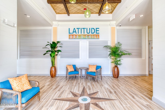 sitting room featuring hardwood / wood-style floors, wood walls, a raised ceiling, and crown molding