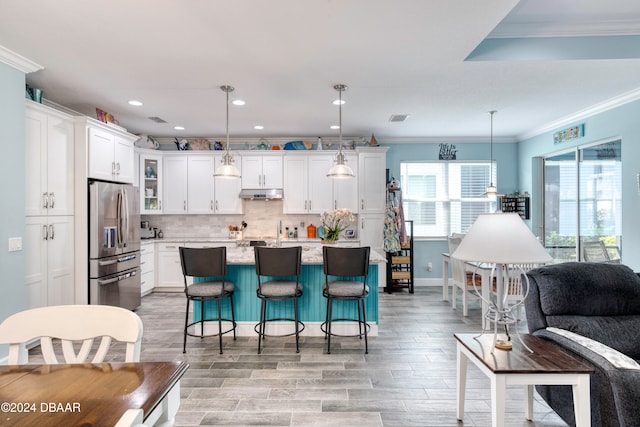 kitchen with decorative light fixtures, a center island, white cabinets, stainless steel fridge, and light wood-type flooring