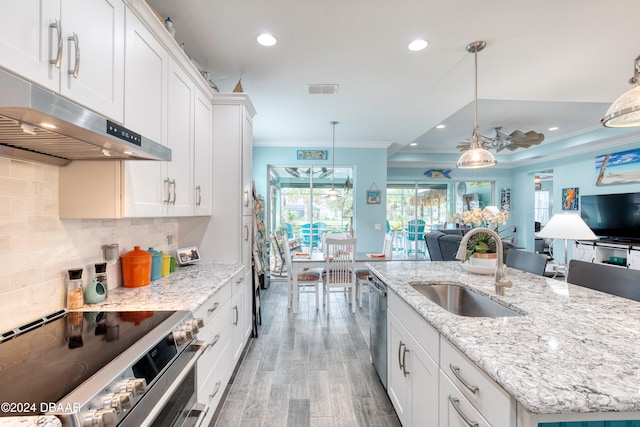 kitchen with white cabinetry, appliances with stainless steel finishes, pendant lighting, and an island with sink