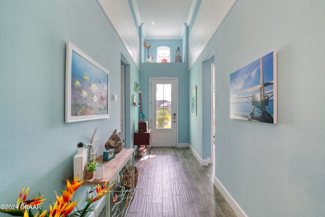 entryway featuring ornamental molding, wood-type flooring, and a high ceiling