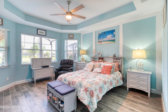 bedroom featuring hardwood / wood-style flooring, ceiling fan, and a raised ceiling