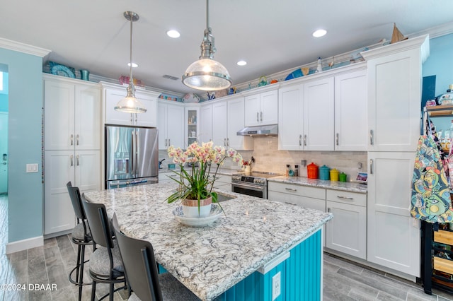 kitchen with pendant lighting, appliances with stainless steel finishes, light hardwood / wood-style floors, and a kitchen island